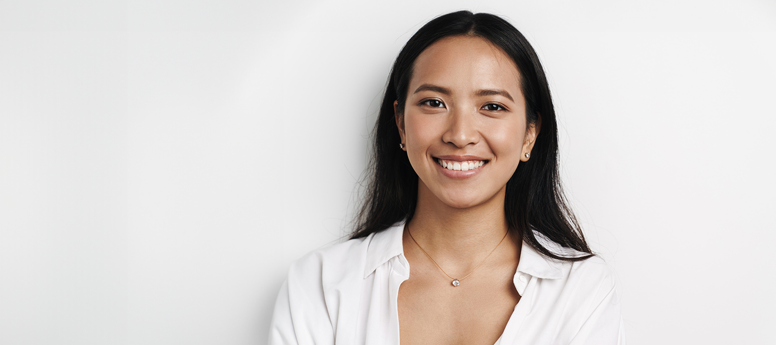 An Asian woman with a radiant smile, posing against a white background.