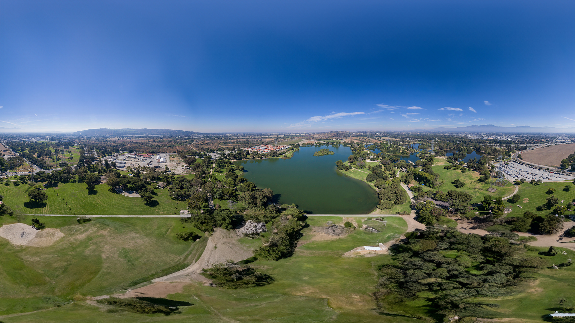 An aerial view of a golf course and community, showcasing a clear sky, green fairways, and residential areas.