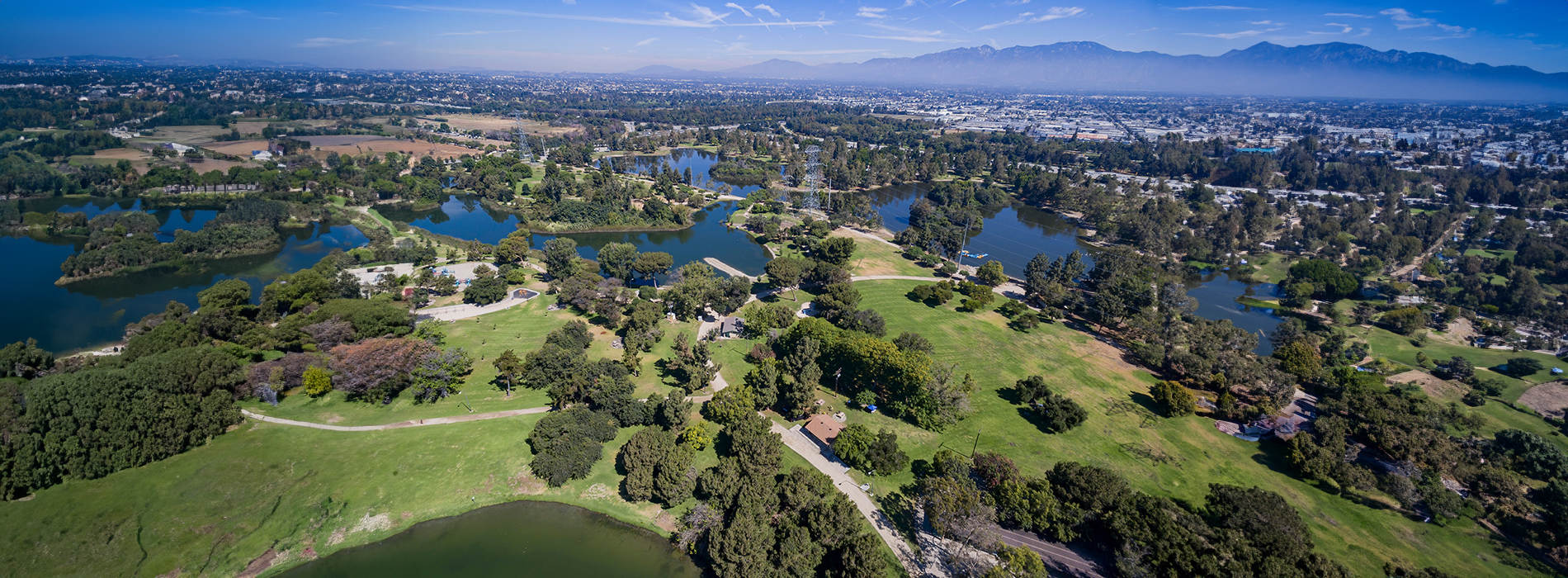 A scenic aerial view of a golf course and lake, with mountains in the distance.