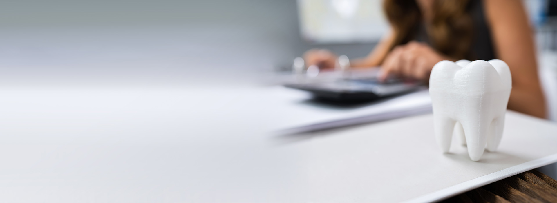 The image shows a person sitting at a desk with a laptop, surrounded by office equipment, and there s an item that resembles a toothbrush holder in the foreground.