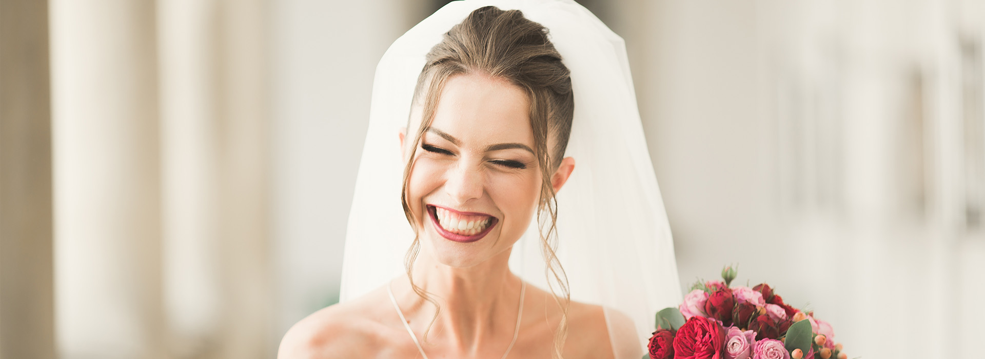 Woman in wedding dress smiling, bride s face obscured by a white veil.