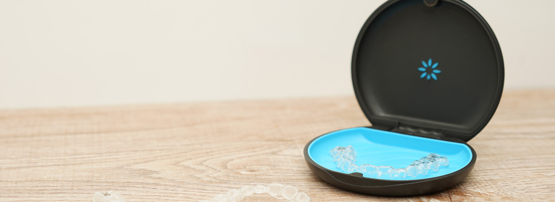 The image displays a smart home device, specifically an Amazon Echo Dot, with its packaging partially removed. It is placed on a surface that resembles wood or a similar natural material.