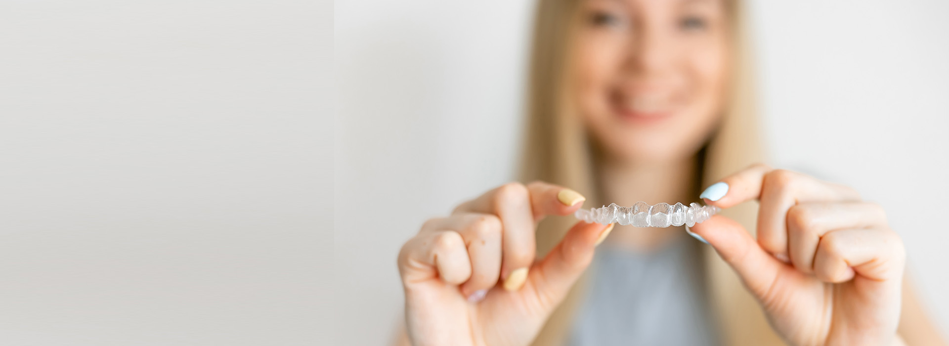 A smiling woman holding a ring in her hand against a blurred background.