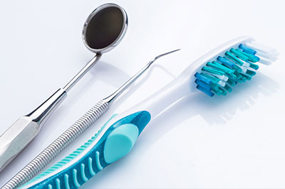 A collection of dental tools including a toothbrush, tweezers, and scissors on a white surface.