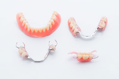 The image shows a set of dentures with teeth and gums displayed, placed on a white background.