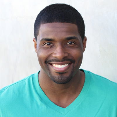 An elderly couple poses for a photo, with the man on the left and the woman on the right, both smiling.