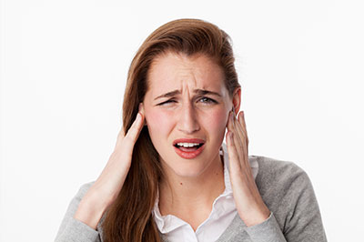 A young woman with her hand on her head, appearing to be in pain or discomfort.