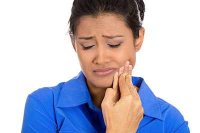 Woman with hand to face, looking down with a concerned expression.