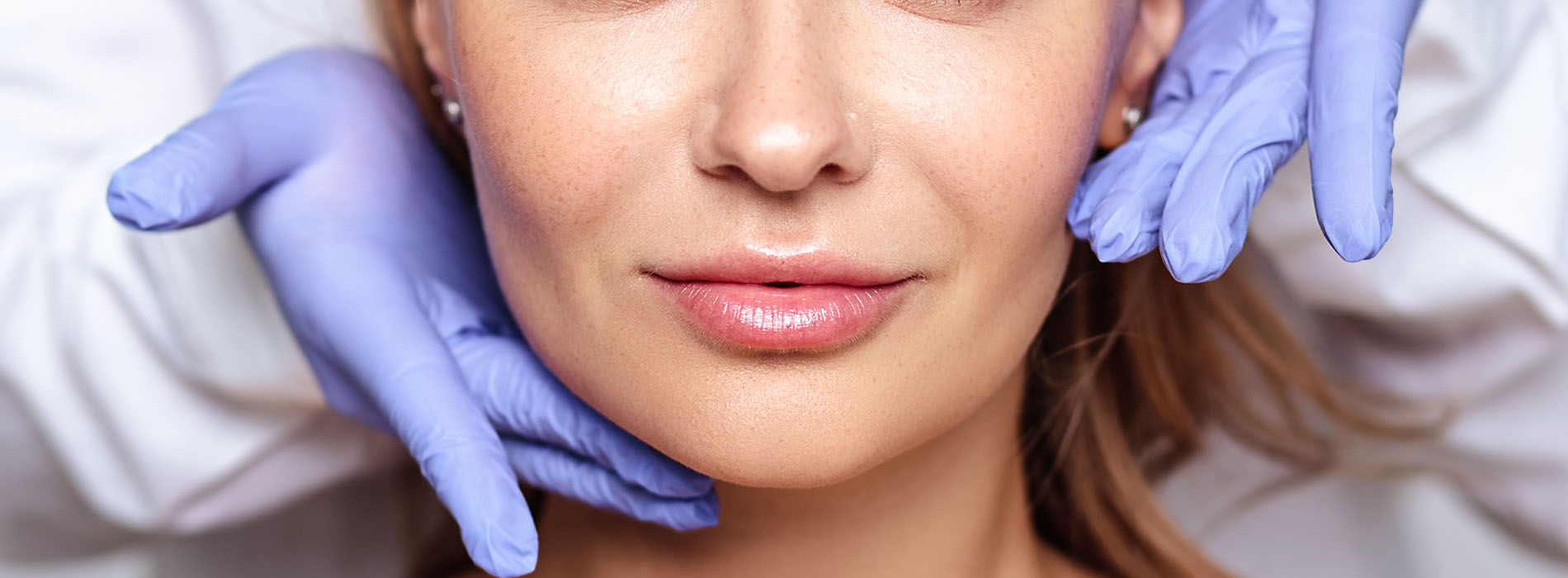 A woman receiving a facial treatment with a medical professional s hand visible, holding a device over her face.