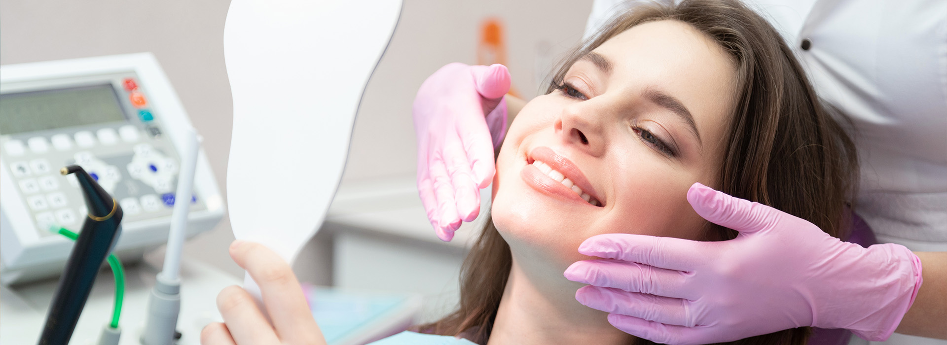 This is an image of a woman receiving dental care, with a dentist examining her teeth using a mirror and dental instruments.