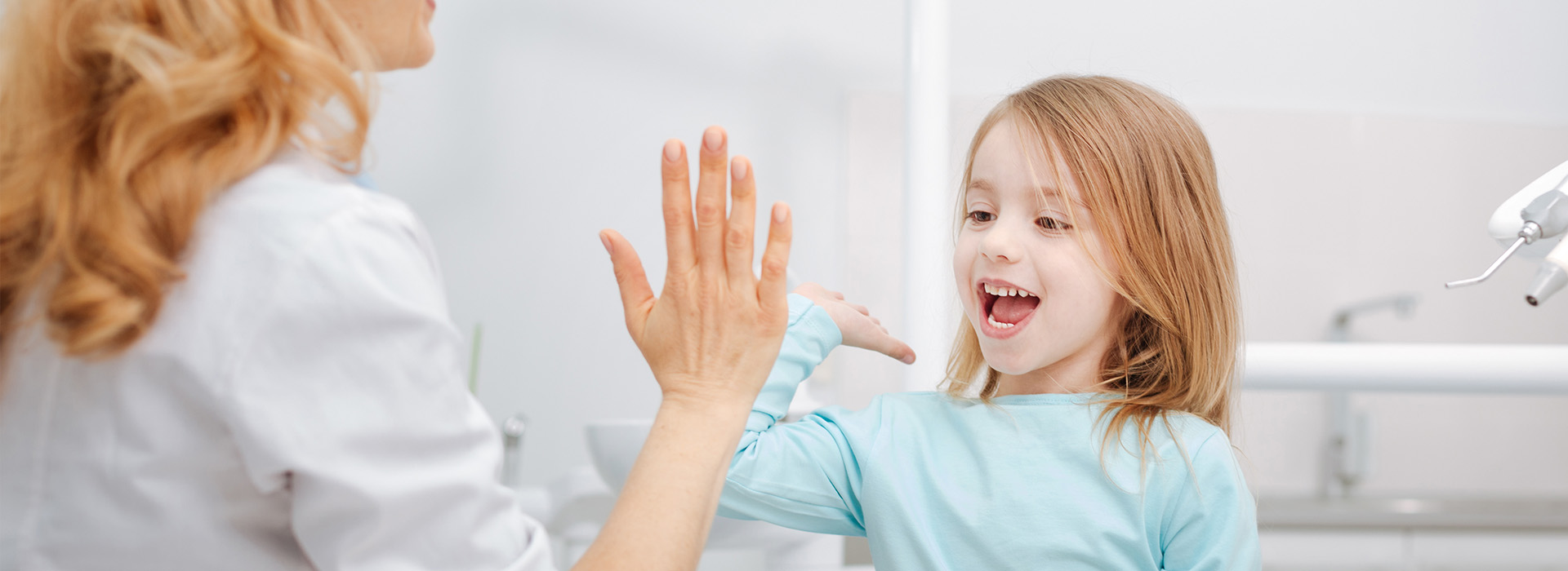 A woman and a young girl interacting in a bathroom setting, with the woman s hand extended towards the child.