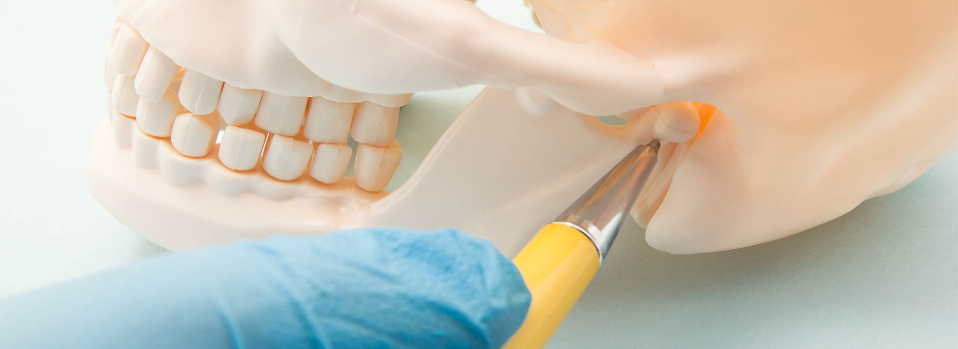 The image shows a close-up of a person s mouth with teeth, being worked on by a dental professional using a drill and holding a small yellow object, possibly a tool or an implant.