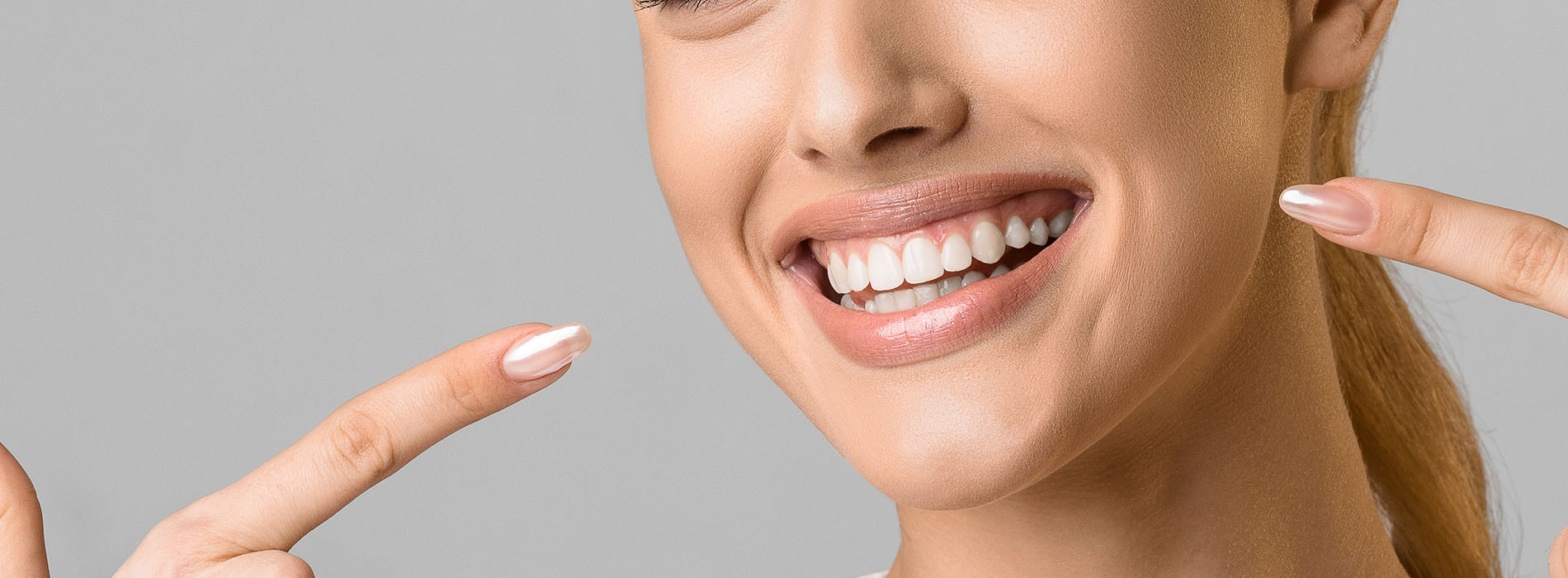 A smiling woman with her hand on her face, showcasing a beauty product.