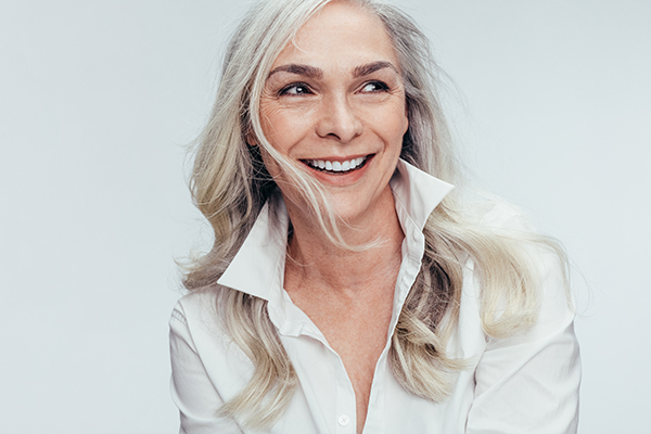 A woman with short blonde hair, wearing a white shirt and smiling broadly at the camera.