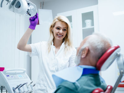 A dental professional is assisting an elderly patient with a dental procedure.