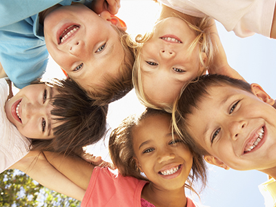 Children of various ages and ethnicities smiling at the camera, forming a circle.