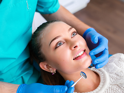 A dental hygienist is performing a teeth cleaning procedure on a patient in a dental office setting.