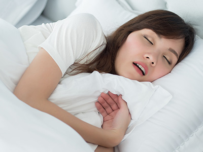 Woman sleeping with eyes closed, mouth slightly open, and hand resting on her chest.