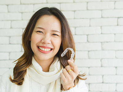 A woman with a radiant smile holds up a toothbrush, showcasing it for the camera.